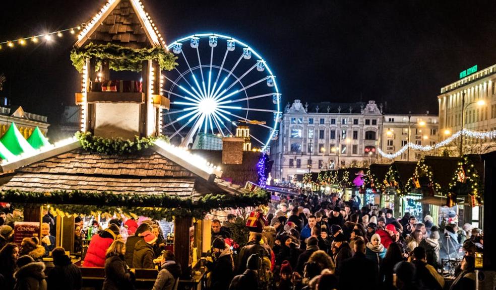 people at a Christmas market with big wheel and stalls